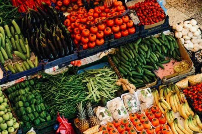 Variety of fruits and vegetables arranged in crates at a market stall.