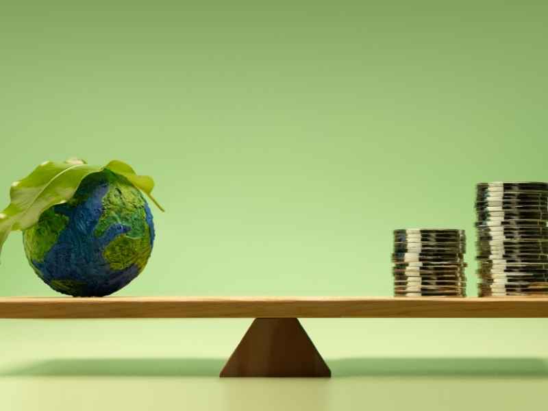 Earth on one side of a balance scale and stacked coins on the other, symbolizing the balance between sustainability commitments and financial performance under ESG frameworks.