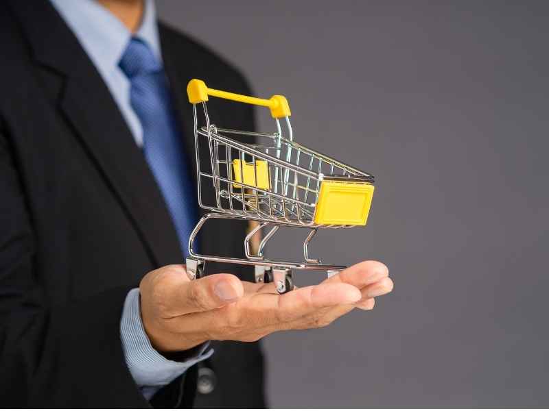 Executive holding a small shopping cart to represent consumer markets and economic inclusion as key components of Building Investor Confidence.
