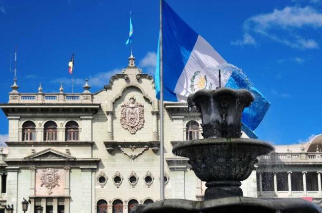 Historic building and monument with the Guatemalan flag, representing national identity and civic institutions.