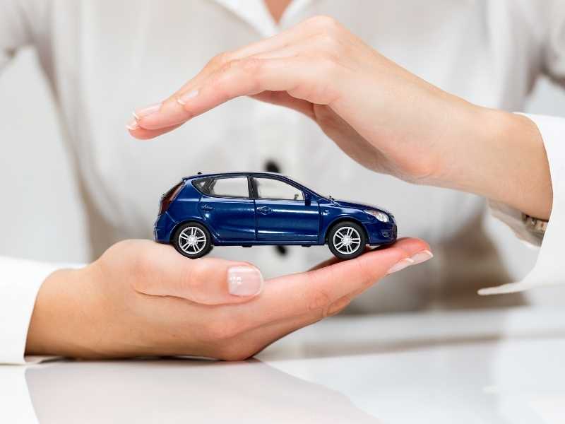 Hands shielding a small toy car, symbolizing comprehensive protection and smart insurance coverage.